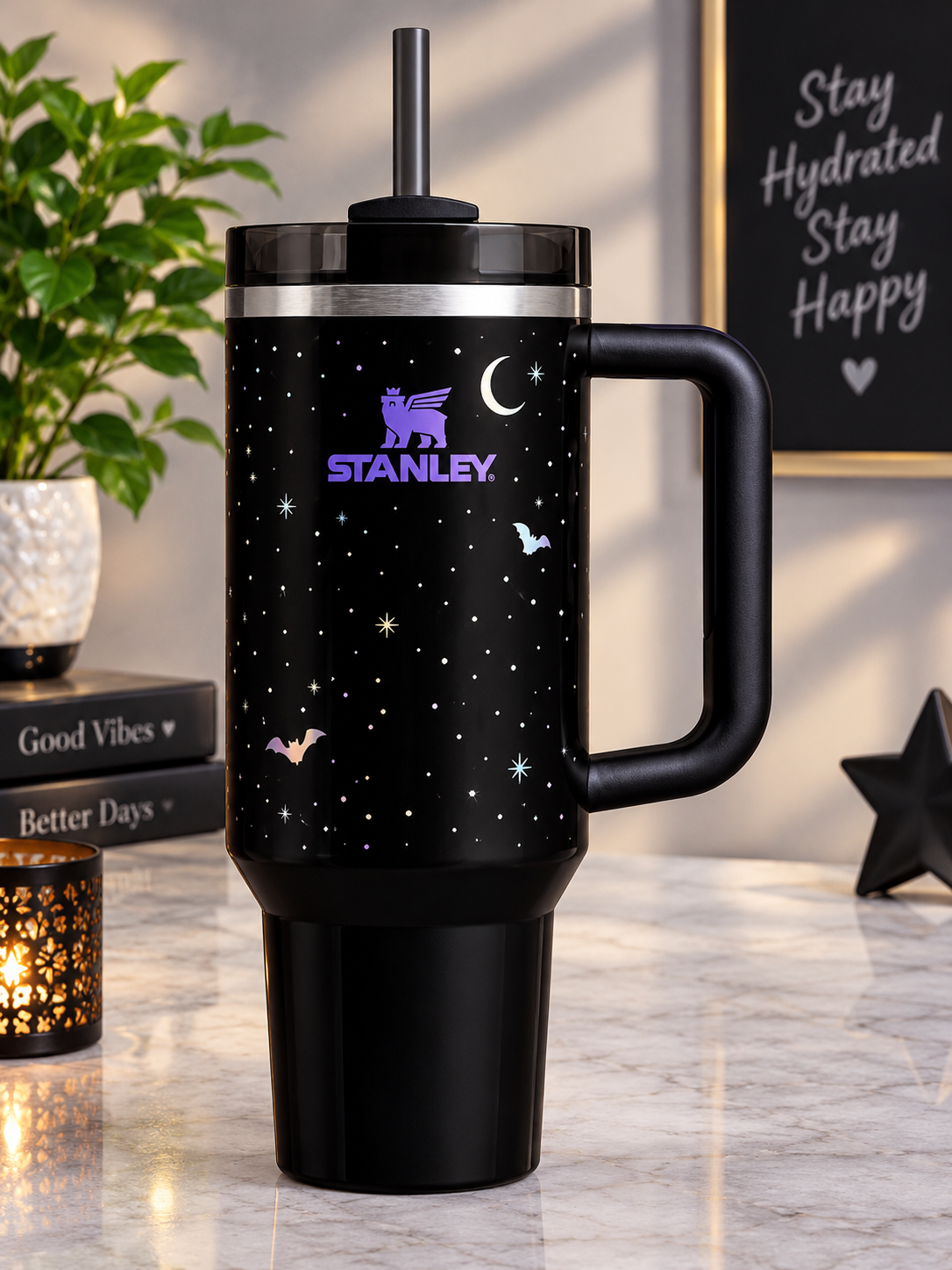 Black handled tumbler with a starry night design, crescent moon, bat graphics, purple logo, dark lid, and reusable straw.