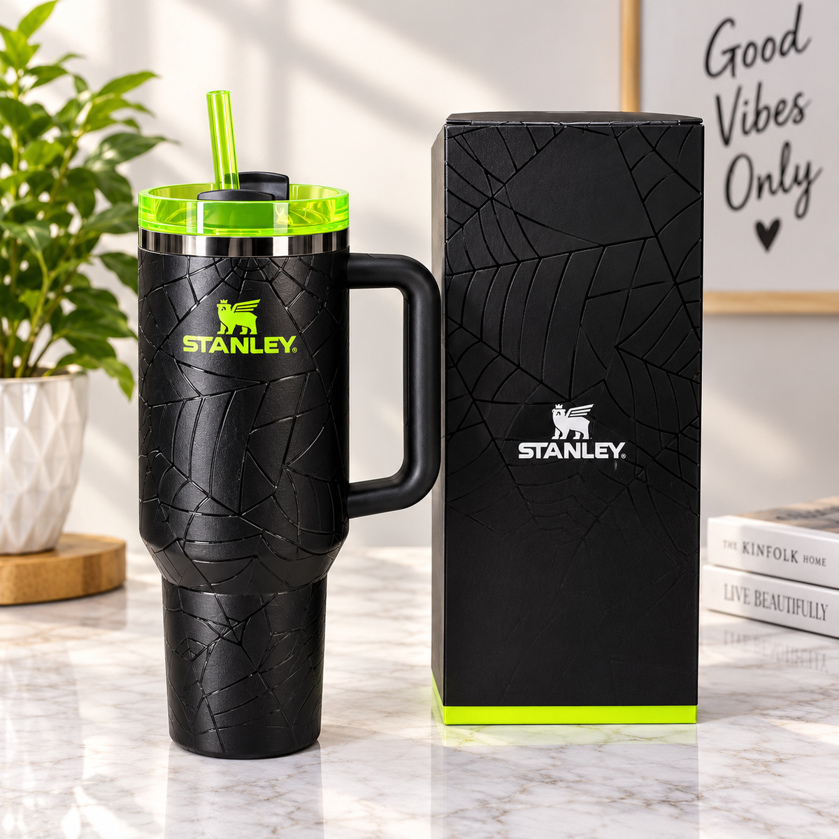 Black textured spiderweb-design tumbler with neon-green lid and straw, black side handle, and matching black presentation box.