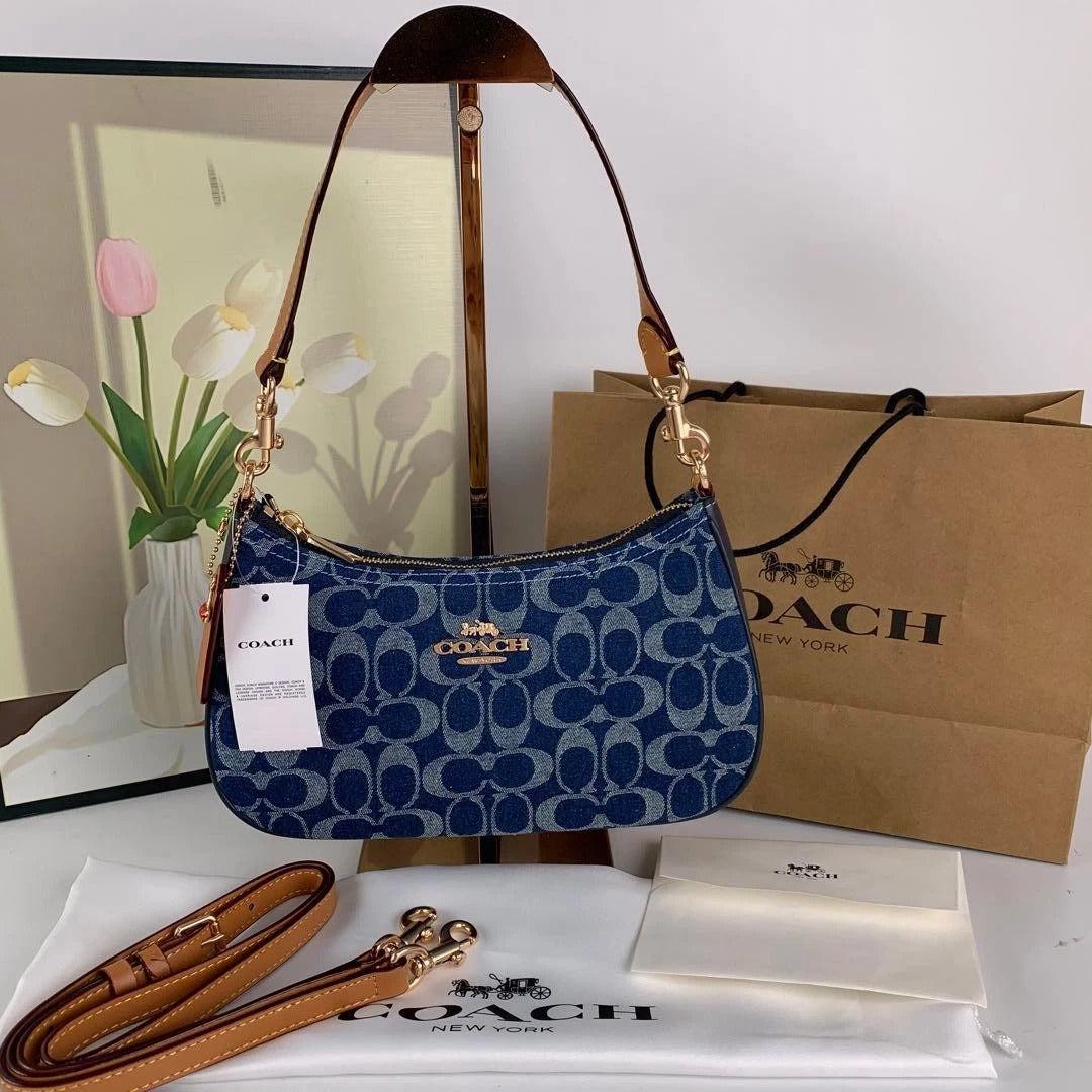 Blue Coach signature-style shoulder bag with gold-tone hardware, curved silhouette, shoulder strap, and additional detachable strap.